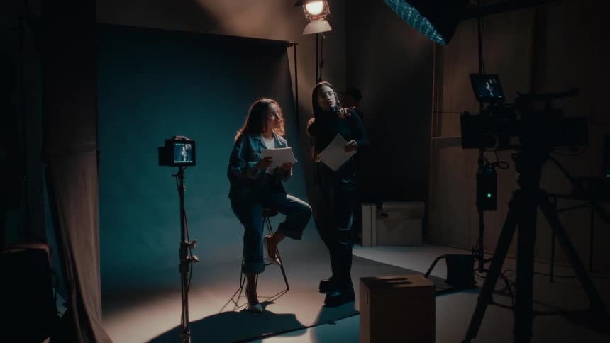 Two women talking inside a studio with cameras and lights