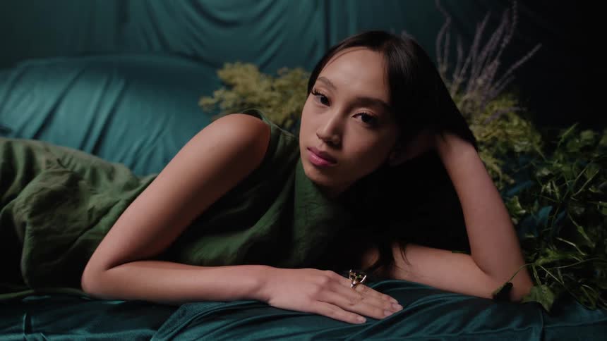 An asian woman lies on a couch and stares