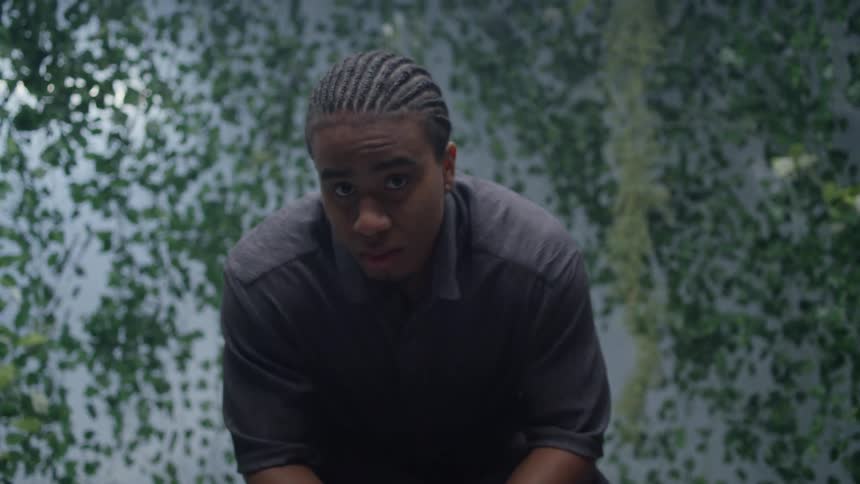 Man sitting in a chair in a studio with foliage around him