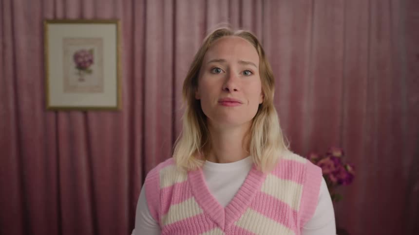 A woman makes faces as if checking herself in a mirror