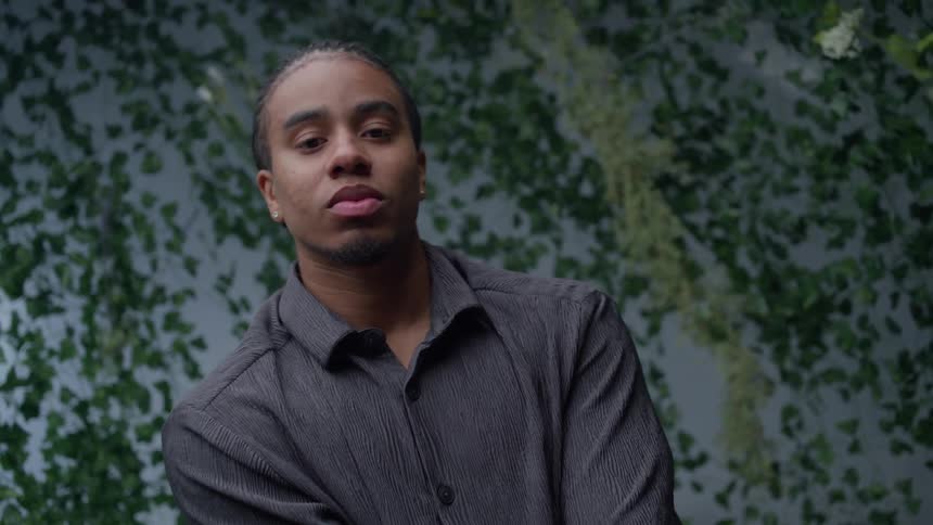 Portrait of a model in a buttondown shirt inside a studio decorated with leaves