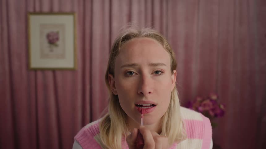A woman is putting on lipstick