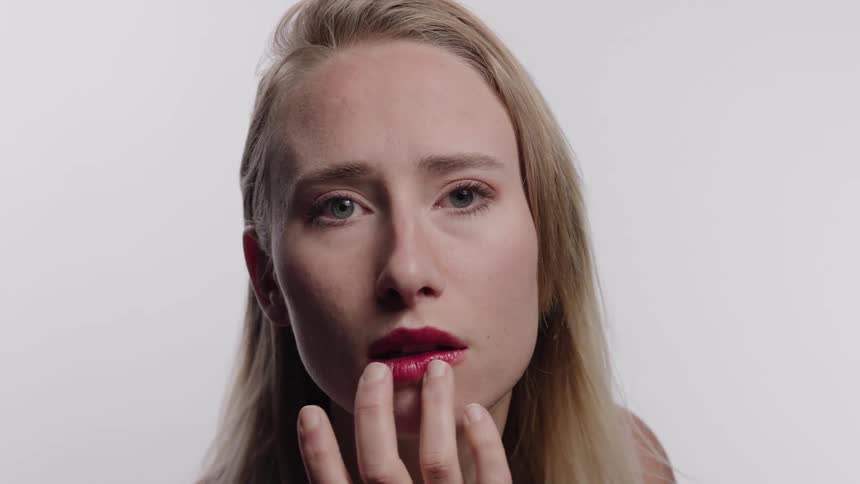 A woman rubs lipstick on her lip