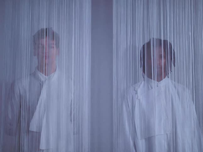 Two male fashion models behind string curtains