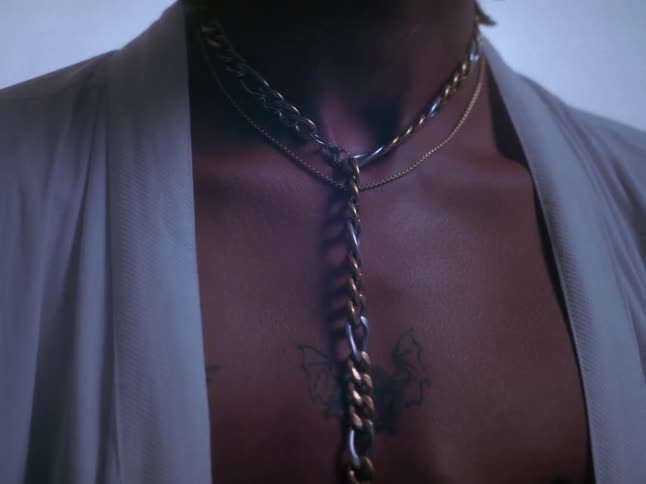 A male model shows off a necklace and belt buckle