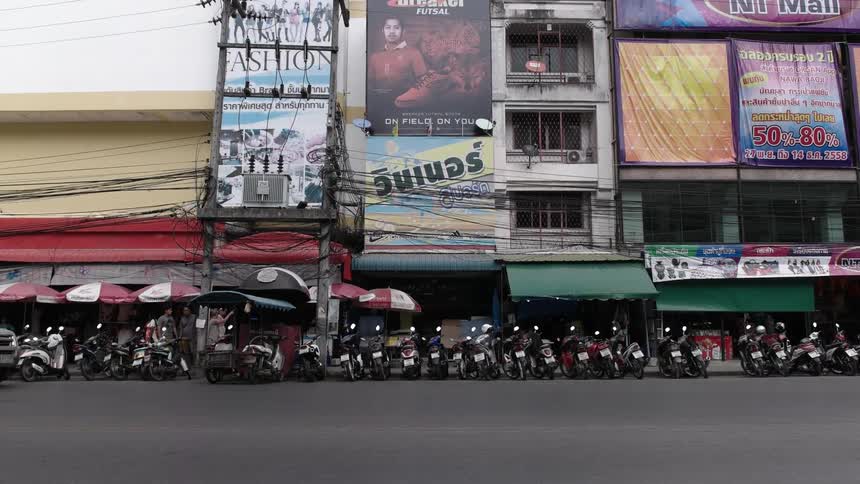 Mopeds are parked in a line in front of city shops