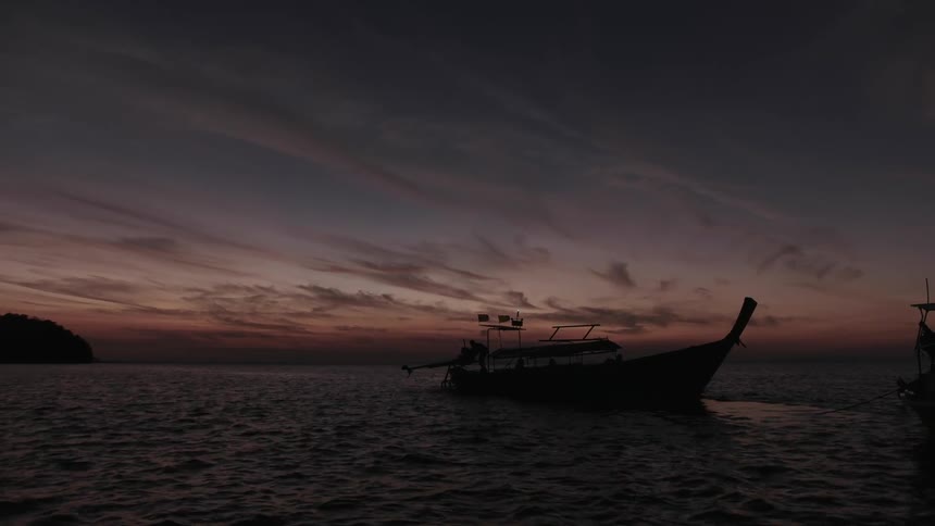 Boat floating on a large body of water at sunset