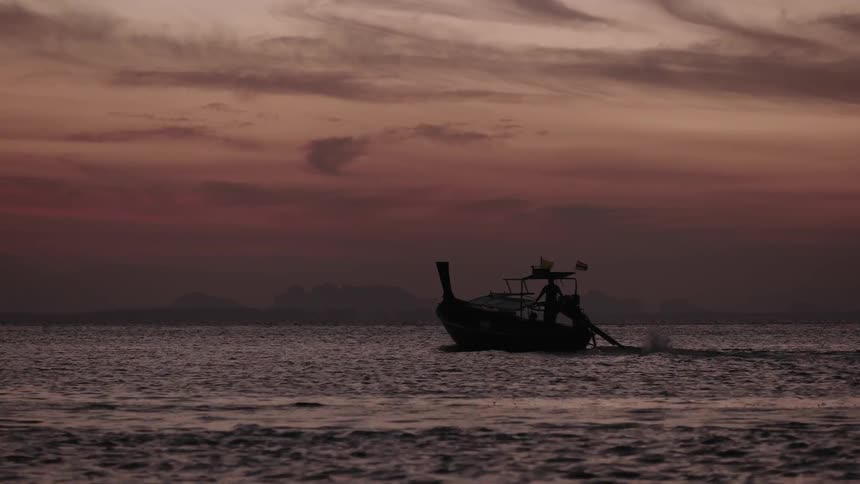 A boat floats on a body of water at sunset
