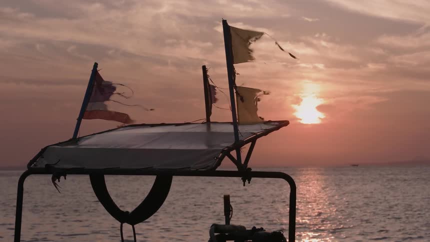 Ripped flags on a boat waving in the wind at sunset