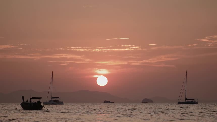 Boats floating in a body of water at sunrise