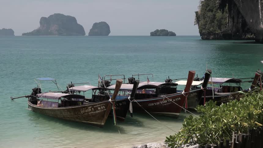 Tied up boats rocking in the waves of a teal blue sea