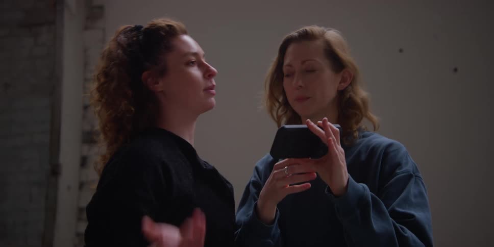Portrait of two friends talking while discussing what they watch on a cell phone