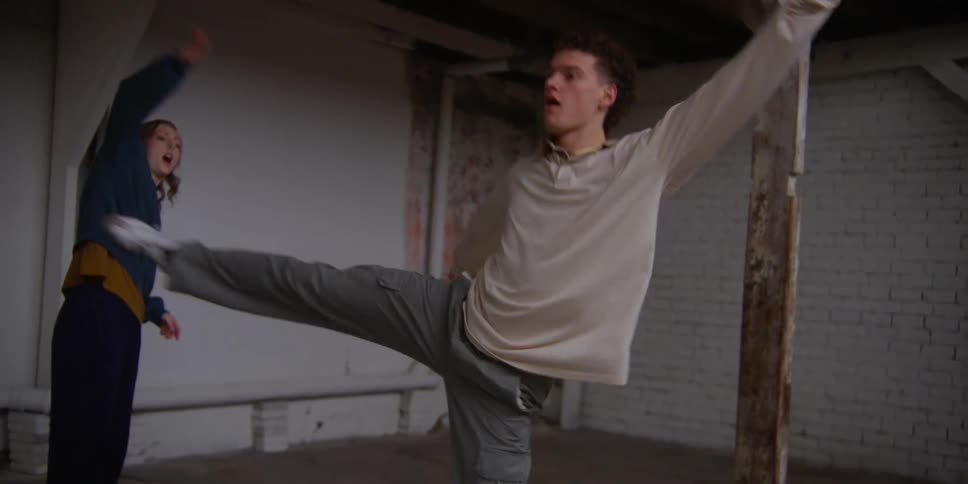 Female choreographer in dance studio guides male dancer through routine