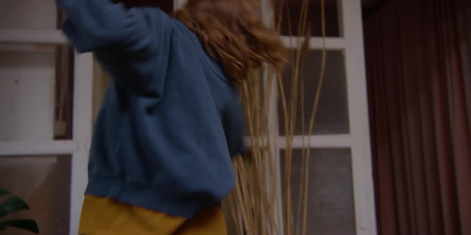 Woman dancing inside the room and then picking up her cell phone on a table