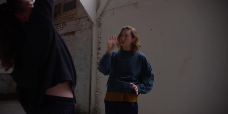 Female choreographer guides dancer through dance routine in studio with high windows