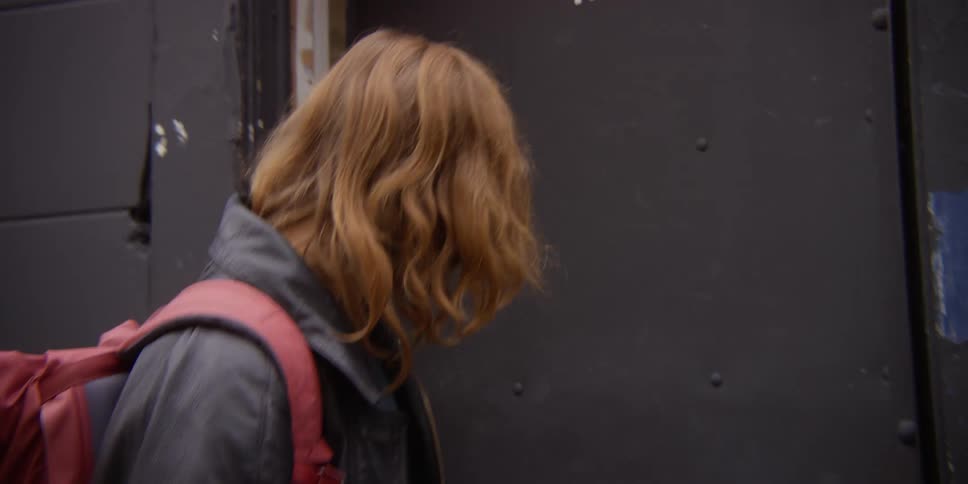 Two smiling women exit a building and walk through a gate