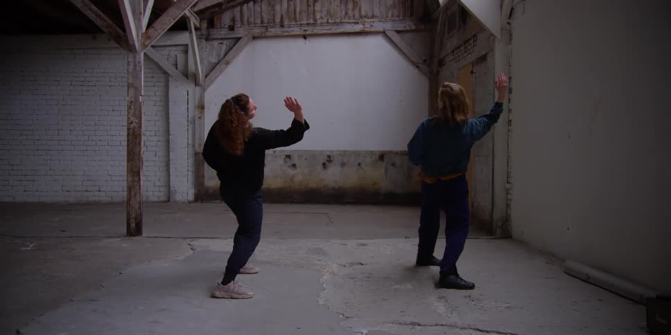 Two women inside an indoor space practicing a dance choreography