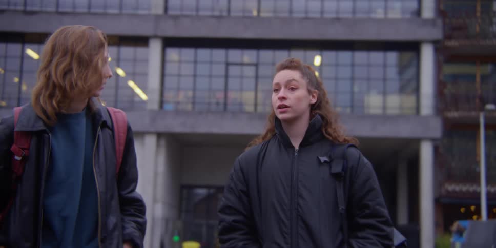 Two females talking while walking on the street at midday