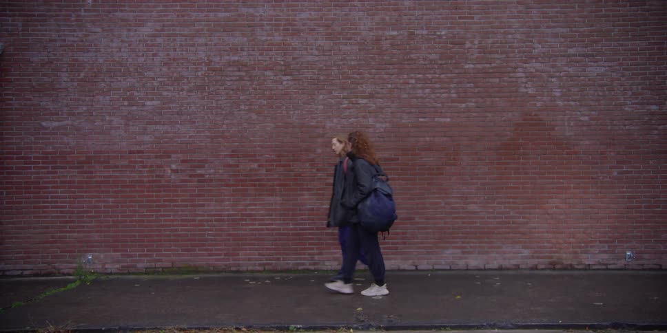 Two female pedestrians walk past brick building
