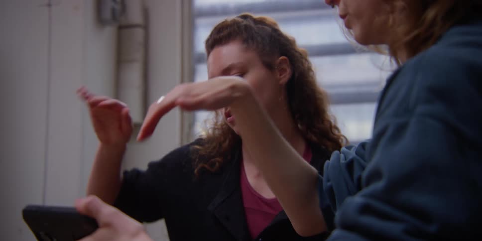 Portrait of two friends looking at the phone and practicing a hand choreography