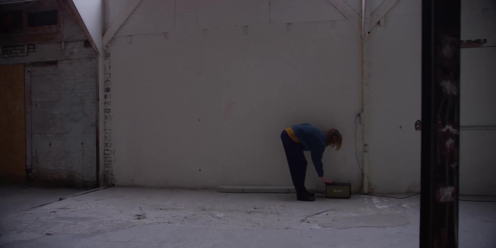 Woman guides another woman through shoulder rolls while standing in large empty room