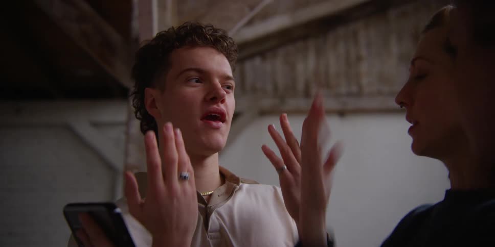 Dancer shows man and woman how to dance using smartphone