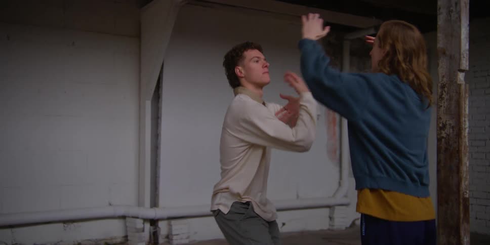 Man and woman inside an indoor space practicing a choreography