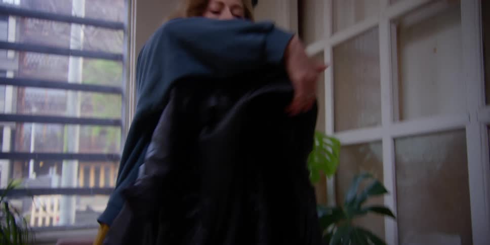 Woman putting on a scarf and a leather jacket