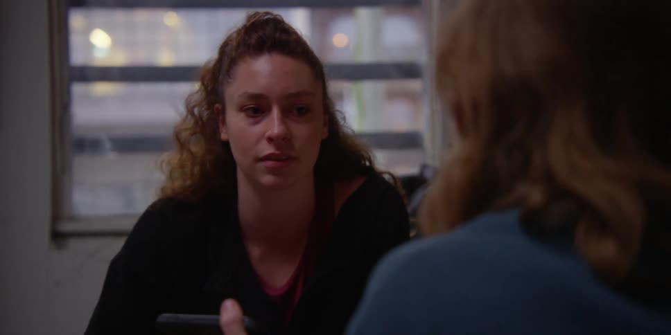 Two women sitting talking and debating something while watching on their cell phone