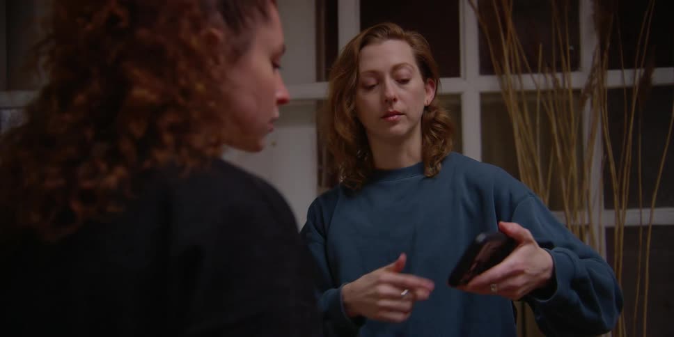 Friends talking to each other and at the same time looking at a cell phone that one of them is holding