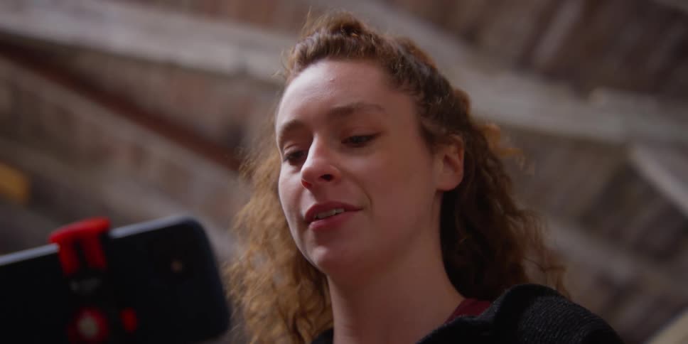 A lady smiling and shaking head while looking down at her mobile phone