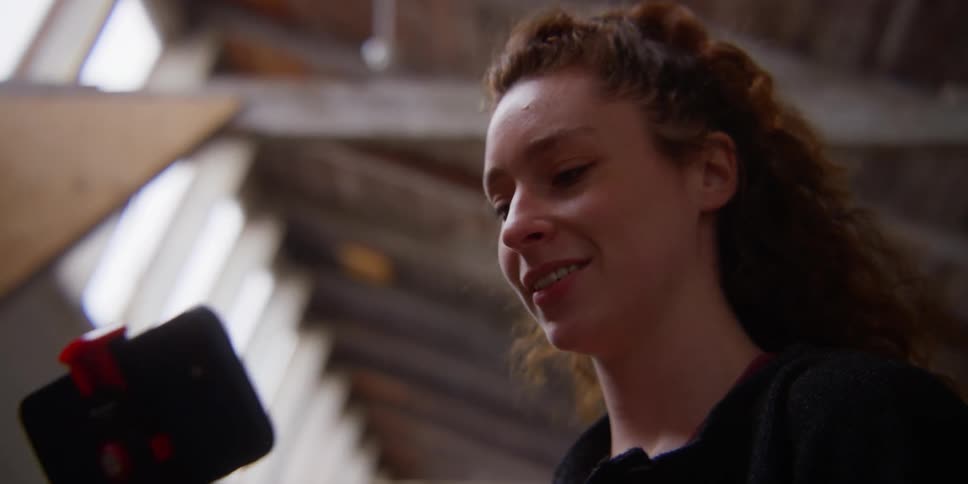 A woman smiles while looking at a smart phone