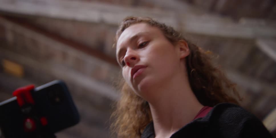 A woman watches a smart phone and practices a dance move