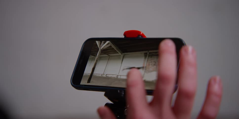A person taps their phone as they watch a video