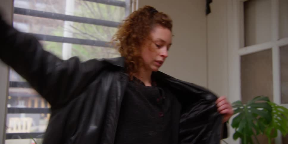A woman puts on her shirt and coat