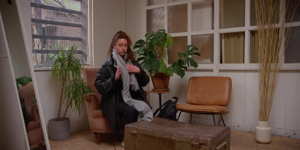 A woman sitting on chairs in the corner of a room