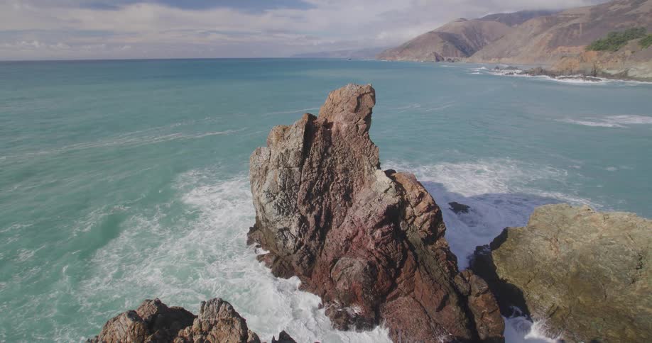 Greenish sea water crashing and climbing rocks on the sea coast