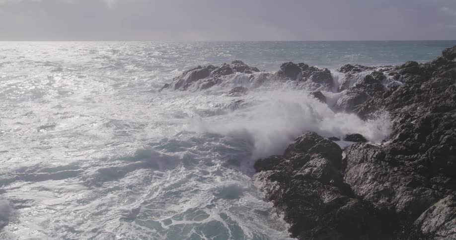 Sea waves break on the rocky shore of the beach