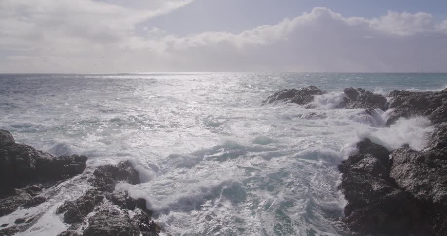 The waves crash against the rocks on the shore