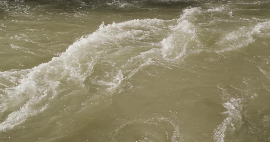 A closeup of turbulent water with waves and foam