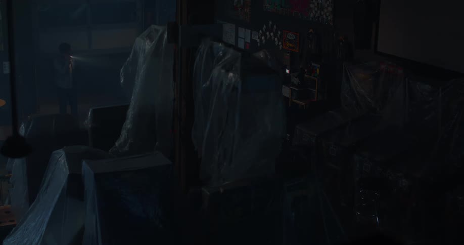 A person with a flashlight in a warehouse with arcade machines