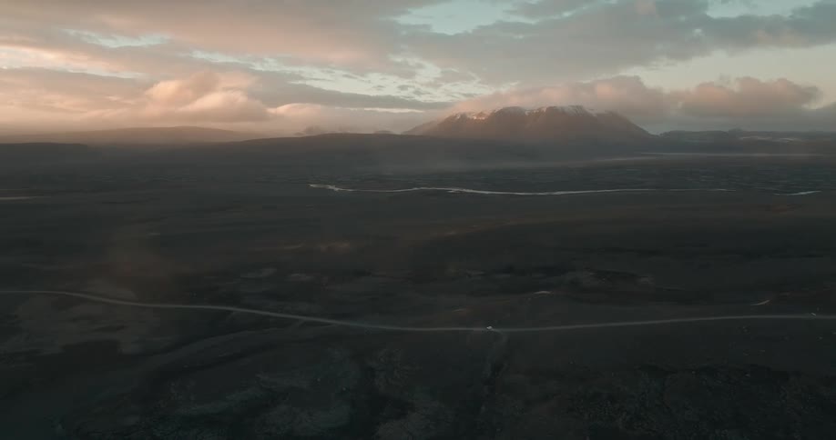 A vast landscape during sunset with mountains in the background and a river