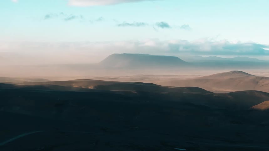 A vehicle moving on a sandy road at sunset