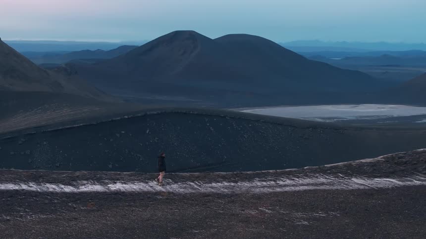 Aerial view of a person walking over the ridge of a mountain