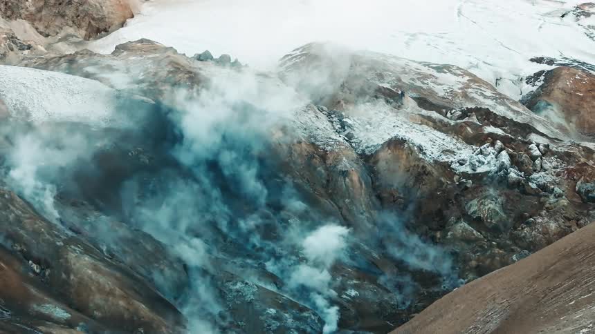 Aerial of an erupting volcanic mountain covered in snow during winter