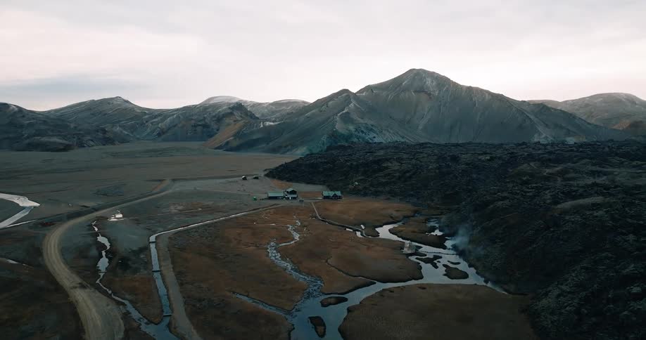 A dirt road passes through a valley with a branching river