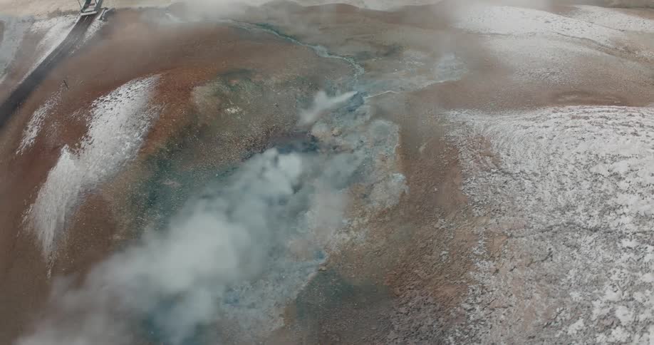 A snowy terrain with geothermal activity captured from the air