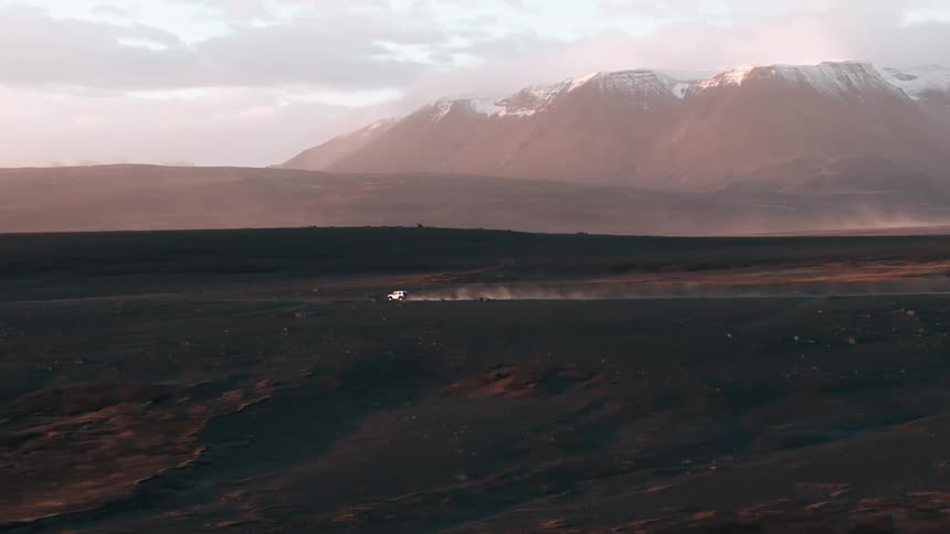A car drives on a road through a mountain valley