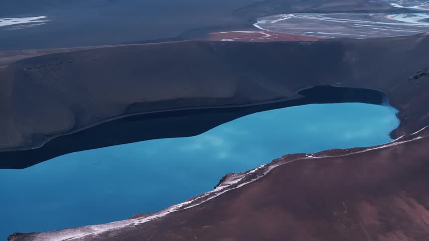 Aerial of a lake surrounded by mountains in the desert during the day