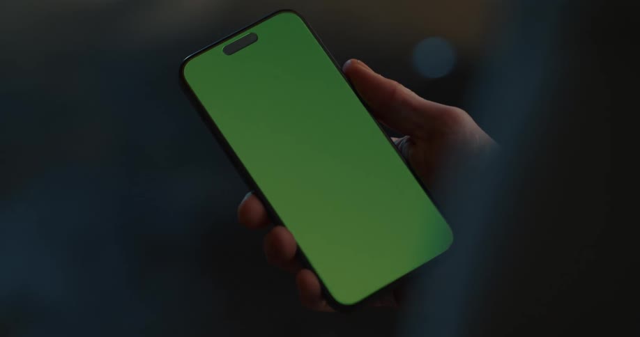 A person holding a smartphone with a green screen in their hand